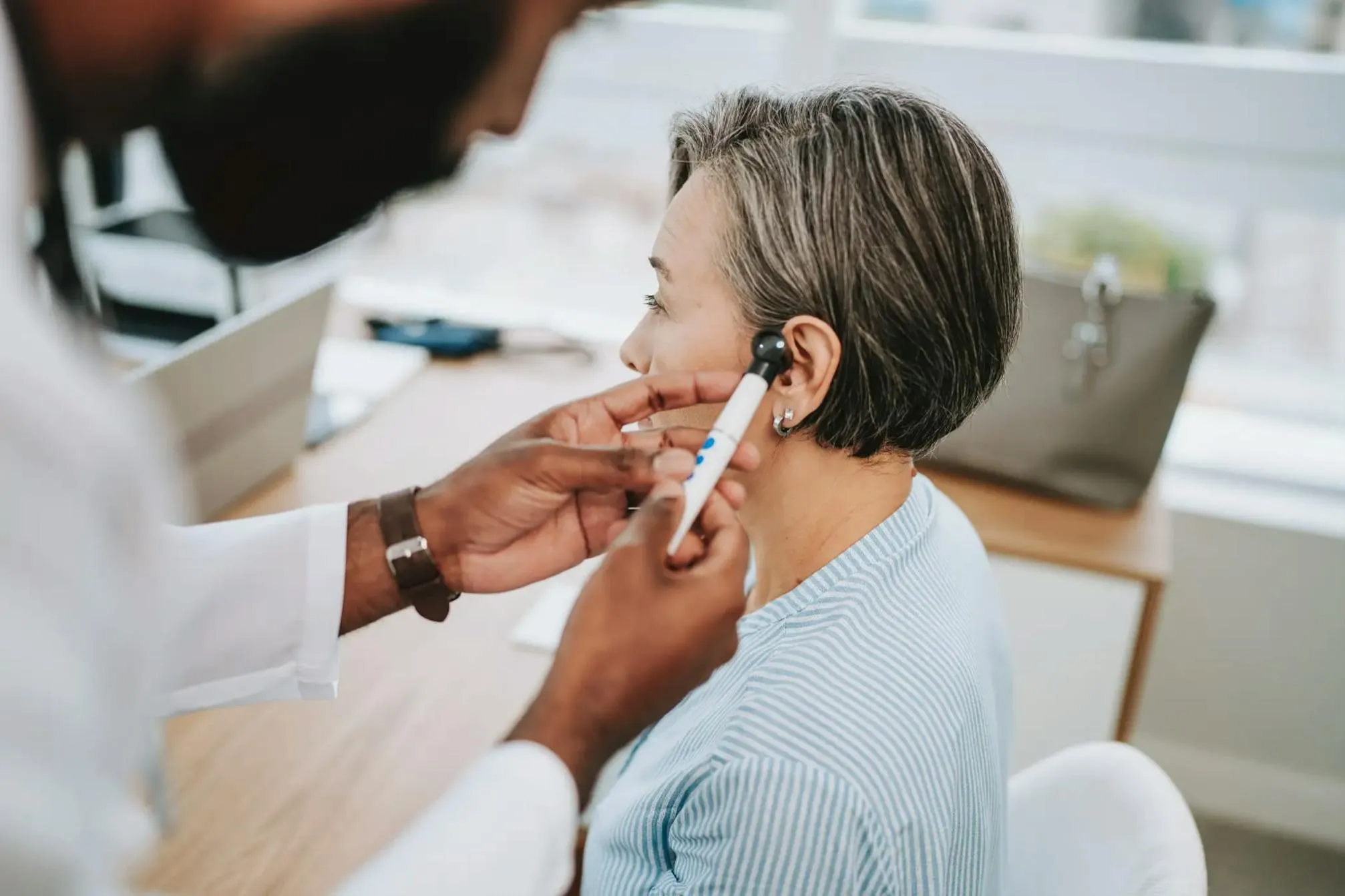 A woman undergoing a professional hearing evaluation conducted by an audiologist.