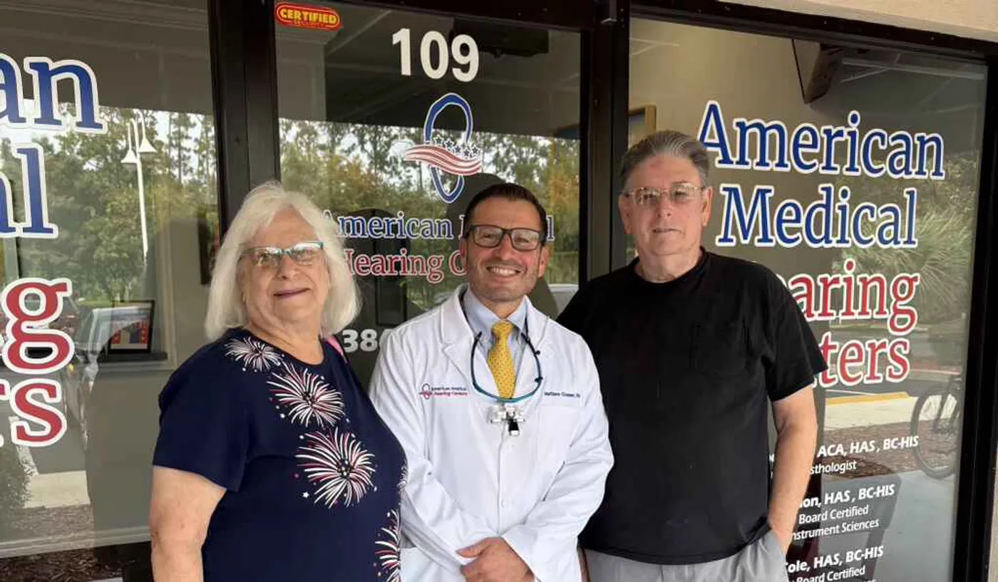 Hearing specialist standing with patients outside an American Medical Hearing Centers office